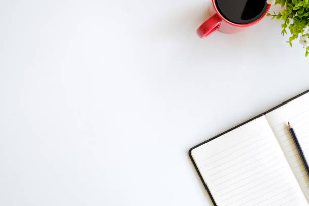 istock Top view workspace notebook and pencil with cup of coffee on white table. 970936680