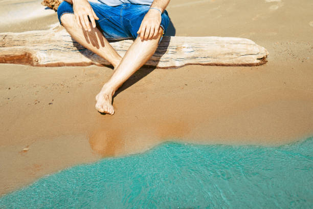 istock guy sitting by the sea 970952588