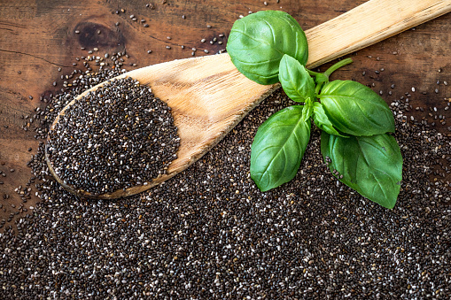 Chia seeds in wooden spoon and basil leaf on wooden background. Super Food.  Healthy eating  concept. Copy space.\