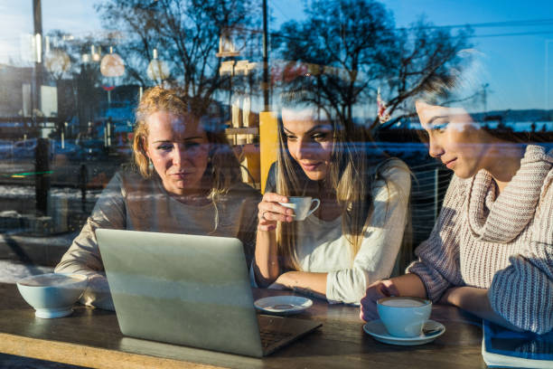 istock Female students looking something on laptop in cafeteria. 970965506