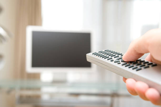 A person using a remote controller on their television stock photo