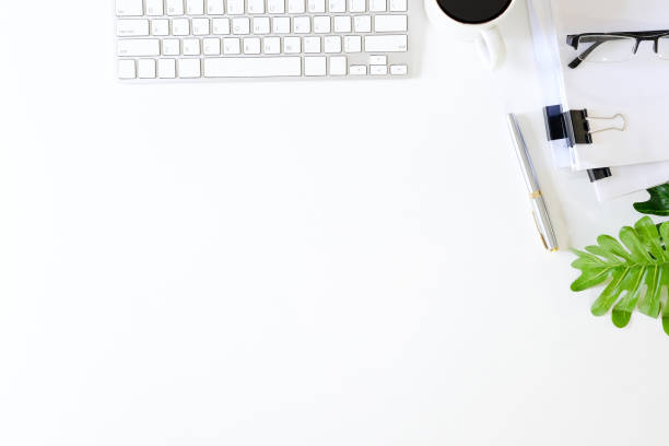 istock Office desk with computer keyboard, pen, coffee cup, glasses, plant and document paper on white table workspace and copy space top view. 970974906