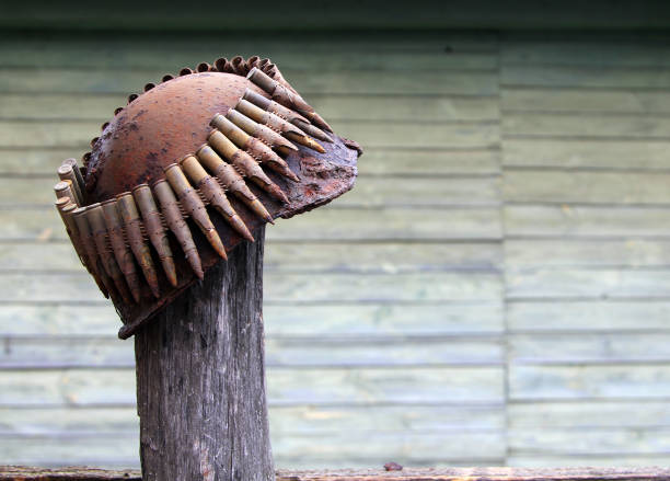 vecchio casco militare arrugginito e cintura mitragliatrice con cartucce su uno sfondo di muro di legno - dachau foto e immagini stock