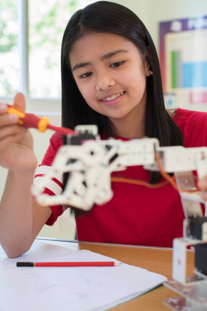 istock Female Pupil In Science Lesson Studying Robotics 971001082
