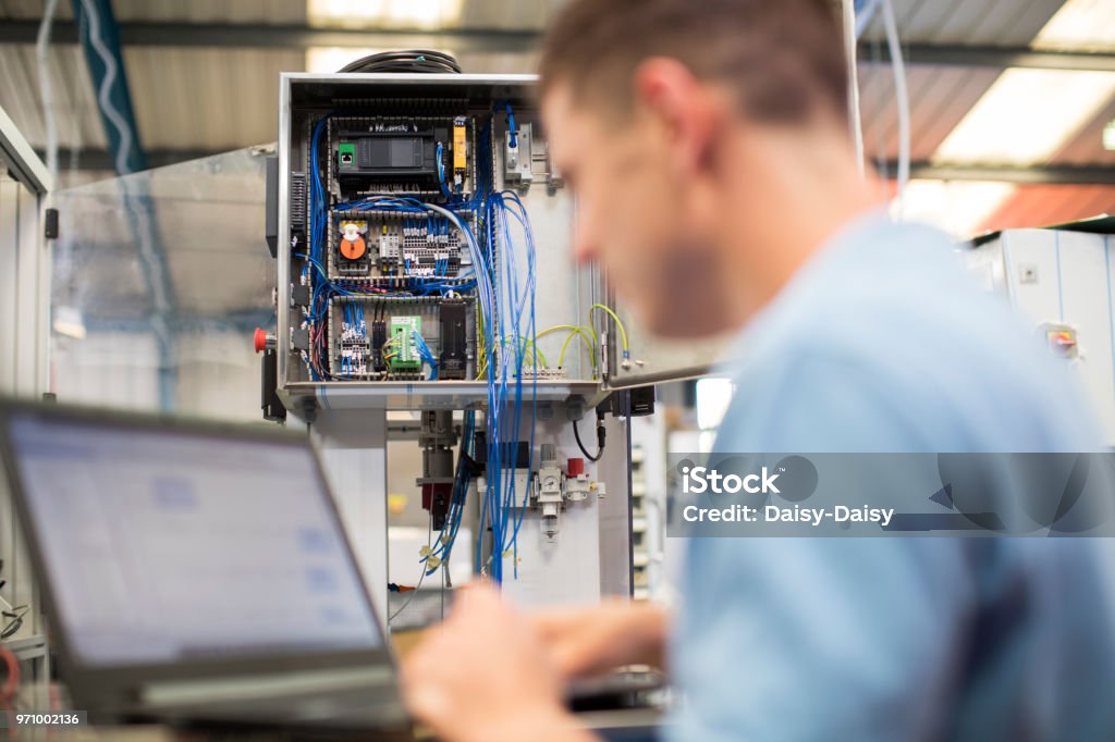 Male Engineer In Factory Using Laptop Computer Electrician Stock Photo