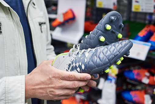 Hands of a man with football boots in a sports store