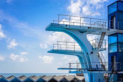 High tower for diving at public swimming pool and summer sky with gull. Vintage Vision.