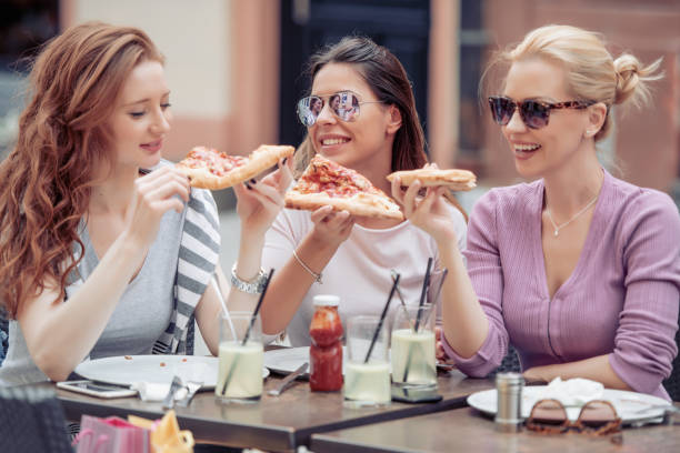 istock Three cheerful girls eating pizza 971025494