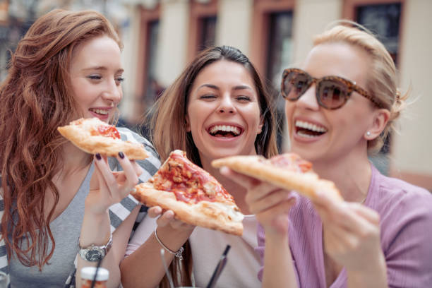 istock Three cheerful girls eating pizza 971025512