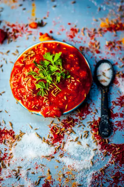 Indian/Asian popular tomato chutney with all its ingredients and spices on a silver surface.