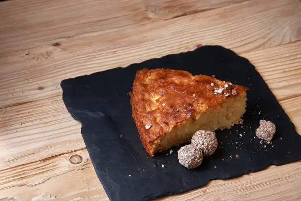 Photo of Apple pie tart on shale board with raisins, nuts and cinnamon is a vintage wooden background texture. Rustic style