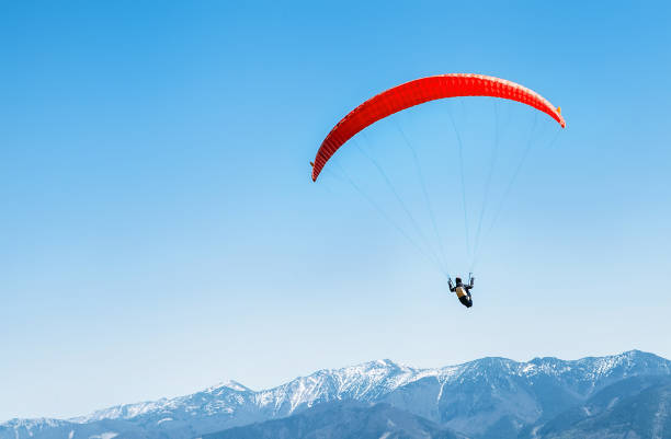 sportsman on red paraglider soaring over the snowy mountain peaks - airplane sky extreme sports men imagens e fotografias de stock