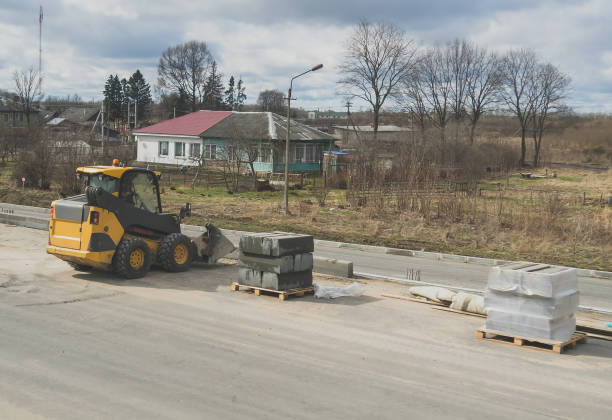 istock Construction of a footpath. Skid-steer loader and curbs. 971043276