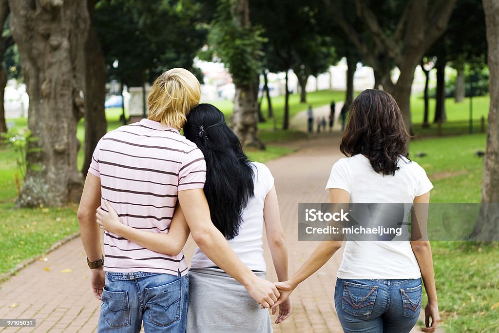 Man holding hands with a woman while another woman holds him young man cheating on his girlfriend with her best friend Infidelity Stock Photo