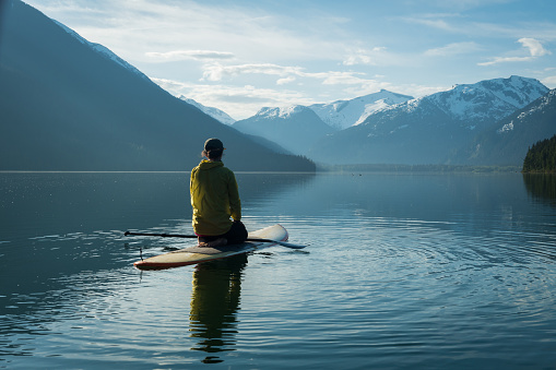 istock Mujer stand up paddle board en un lago de montaña de aguas cristalinas 971053040