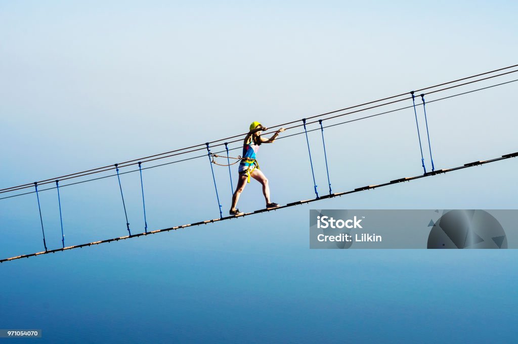 Femme sur le pont de corde de pendaison - Photo de Bleu libre de droits