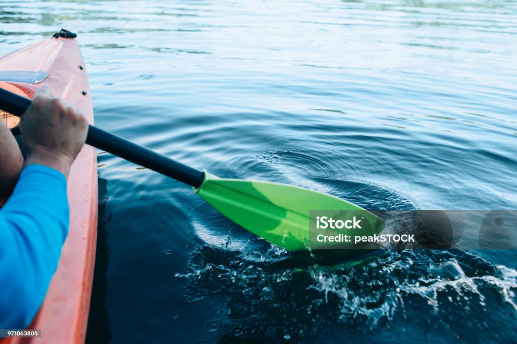 kayaker paddles across a serene lake kayaker paddles across a serene lake, focus on the foreground Kayak Stock Photo