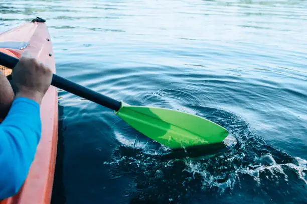 Photo of kayaker paddles across a serene lake
