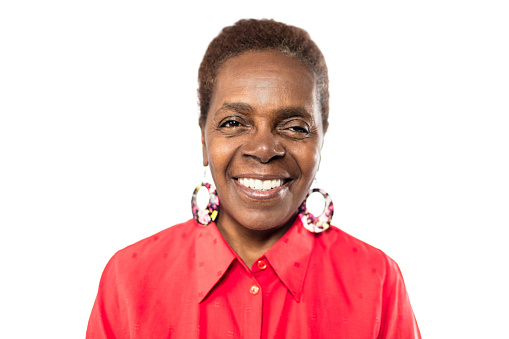 Close up portrait of smiling senior woman with short hair wearing big earrings. Happy mature woman in casuals against white background.