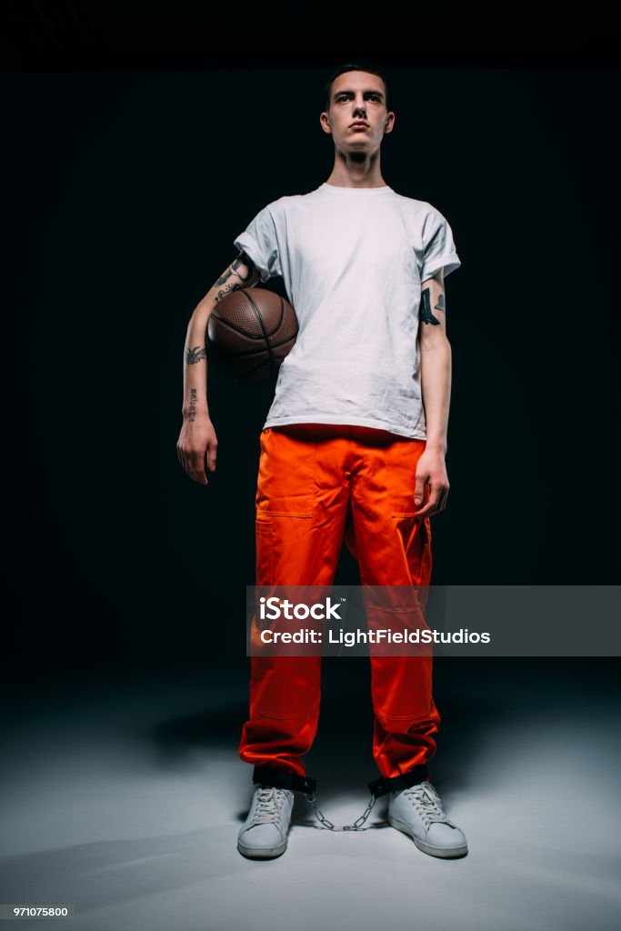 Preso Hombre Joven Vestida Con Pantalones Naranja Y Puños Con Pelota De  Baloncesto Sobre Fondo Oscuro Foto de stock y más banco de imágenes de  Encuadre de cuerpo entero - iStock