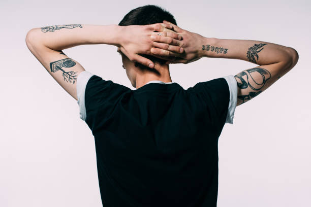 istock Man with tattoos holding hands behind his head isolated on white 971086586