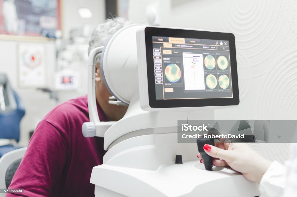 Refractometry. Keratometry. Refraction test. Optometry equipment. health care, medicine, people, eyesight and technology concept - close up of optometrist with autorefractor checking patient vision at eye clinic or optics store Optometry Stock Photo