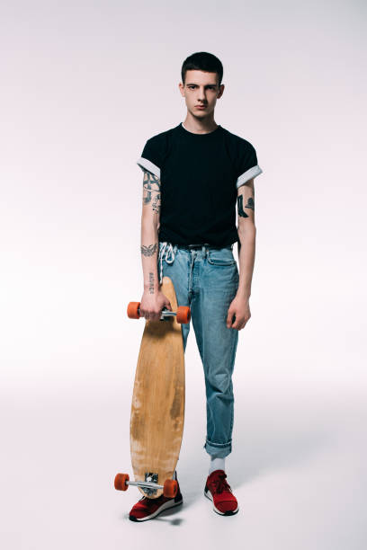 istock Guy with tattooed arms holding longboard on white background 971086936