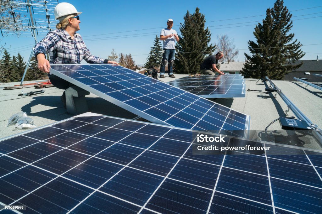 Solar Panel Installation Workers installing solar panels on a residential homes roof. Solar Panel Stock Photo