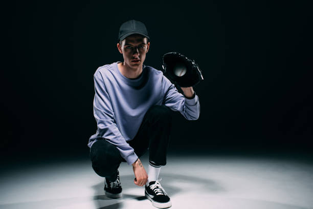 istock Handsome young man with baseball glove catching ball on dark background 971089668