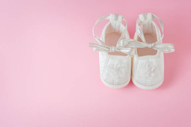 istock White baby shoes on pink background 971089680