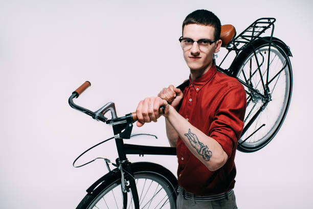 Young man in glasses holding his bicycle on shoulder isolated on white