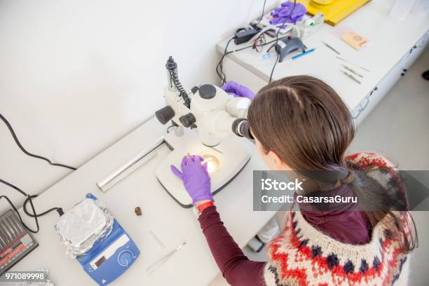 Woman Scientist Researching Material Sample With Microscope Stock Photo - Download Image Now