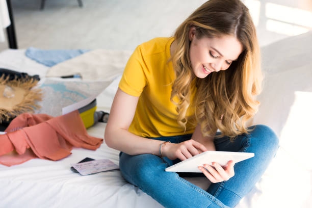 istock beautiful happy girl using digital tablet while packing travel bag 971120726