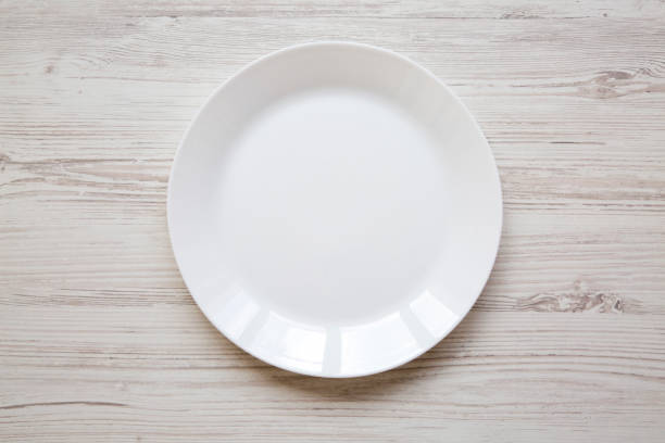 istock White plate on white wooden background, top view. 971141946