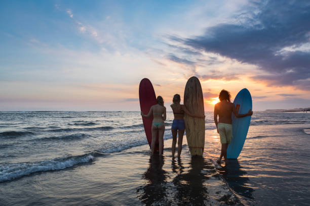 istock Group of three surfers on the beach watching the sunset 971166396