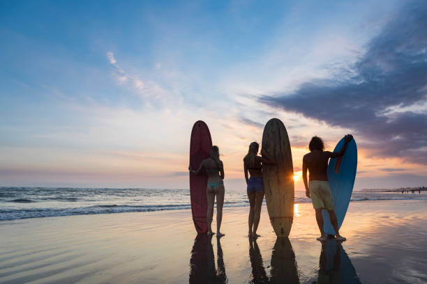 istock Group of three surfers on the beach watching the sunset 971168736