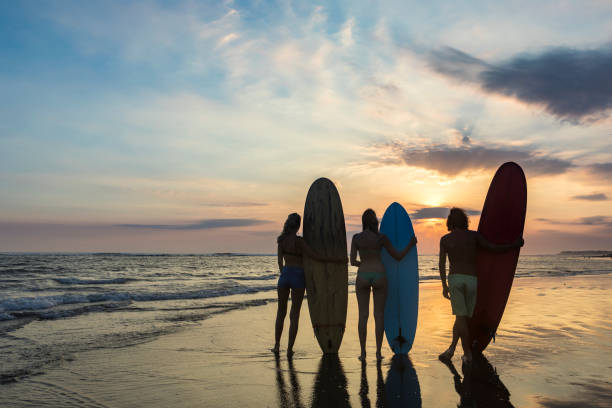 istock Group of three surfers on the beach watching the sunset 971168940