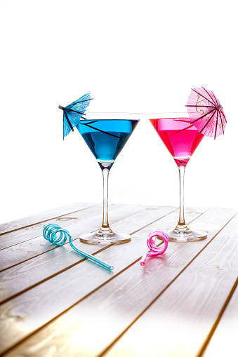 Summer fun alcoholic and non-alcoholic blue and pink fruit cocktail drinks. Party cocktails for the sophisticated party-goer. Cocktail glass, decorative umbrella and curly straw to match!