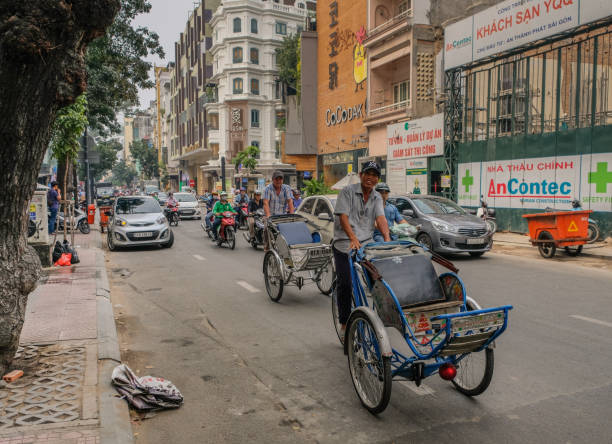 Two bike taxi drivers in Saigon Ho Chi Minh, Vietnam - January 15, 2018: Two smiling men driving taxi bicycles through the streets of Ho Chi Minn vietnamese man taxi motorbike driver stock pictures, royalty-free photos & images