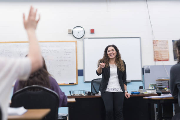 istock Ethnic teacher points to one of her students with a raised hand 971187420