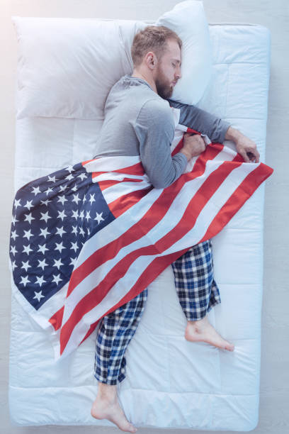 Young mixed race woman lying down on the field and on the American flag