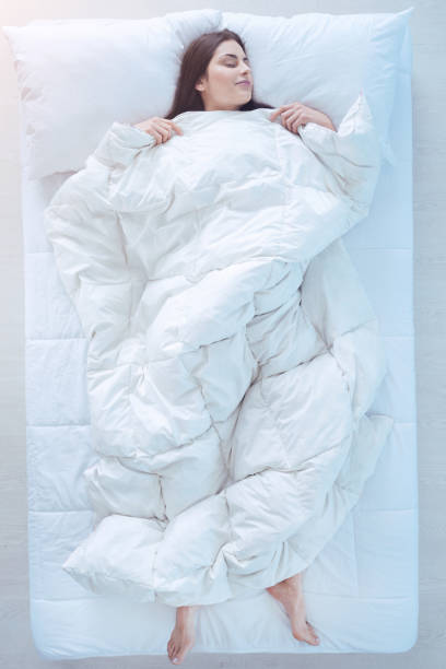 istock Young lady sleeping in bed with duvet over 971190328