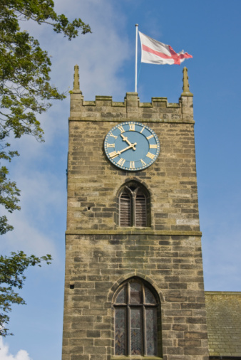 A stone and concrete clock tower with British flag