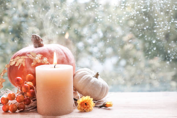 istock Burning candle, Hokkaido pumpkin and Fall decorations on a window board on a rainy day 971198544