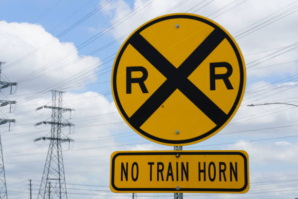 Railroad crossing sign in the countryside on a cloudy autumn day. Colouful autumn trees are visible in background. Copy space.