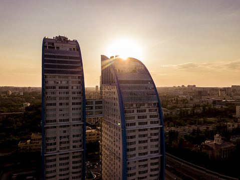 silhouette of double tall skyscrapper with bridge between them against the sunset