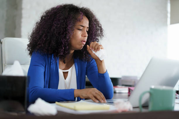 афроамериканка, работающая дома, кашляет и чихает - cold and flu flu virus sneezing illness стоковые фото и изображения