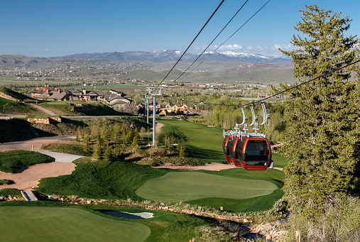 Gondola cables and three cabins suspended over a golf course.