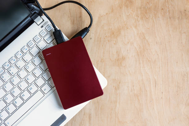 istock Modern storage, external hard drive and laptop keyboard  on wooden table background. 971273292