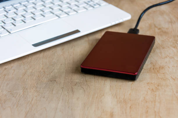 istock Modern storage, external hard drive and laptop keyboard  on wooden table background. 971273294